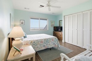 Un dormitorio con cama, escritorio, lámpara, cómoda, televisor y armario.