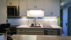 A modern kitchen with white cabinets, a stainless steel refrigerator, a microwave, a sink, and a coffee maker. - OCEANFRONT Midisle Prvt Pool 3New Baths,Kitchen,Floors, AC,Total Renovation!     (Fripp Island)