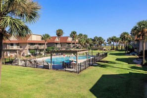 Un resort con piscina, palmeras y un césped bien cuidado.