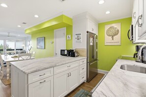 Una cocina moderna con armarios blancos, microondas integrado y refrigerador de acero inoxidable.