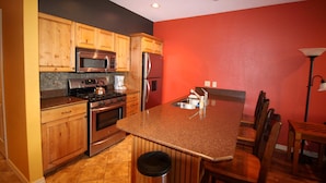 A kitchen with wooden cabinets, stainless steel appliances, and a red accent wall. - Right in the Heart of Park City (Park City)