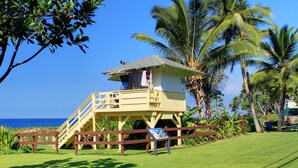 A lifeguard tower with a staircase, surrounded by palm trees and a clear view of the ocean.