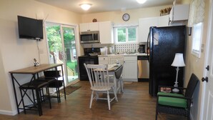A compact kitchen with a dining area, a microwave, a refrigerator, and a television.