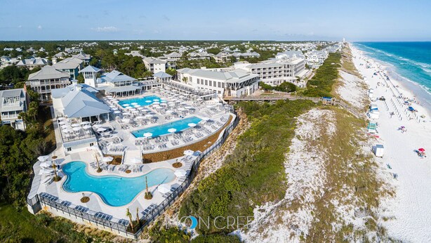 Vue aérienne d’un complexe hôtelier doté d’une grande piscine, d’une plage et de plusieurs bâtiments.