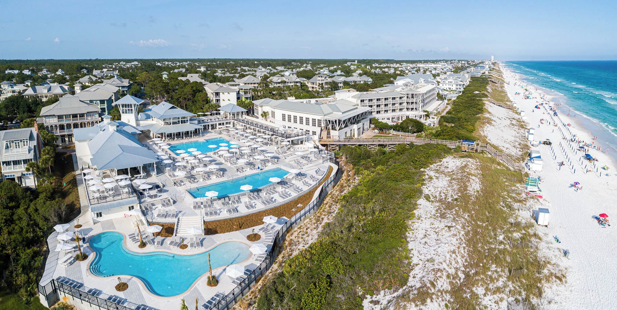 Vue aérienne d’un complexe hôtelier doté d’une grande piscine, d’une plage et de plusieurs bâtiments.