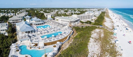 Vue aérienne d’un complexe hôtelier doté d’une grande piscine, d’une plage et de plusieurs bâtiments.