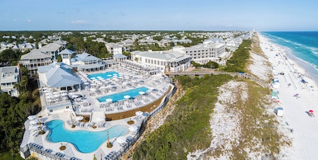 An aerial view of a resort with a large pool, beach, and multiple buildings.