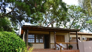A two-story house with a brick exterior, a tiled patio, and a wooden staircase leading to the entrance. - Hotel La Quinta (Paraguari)
