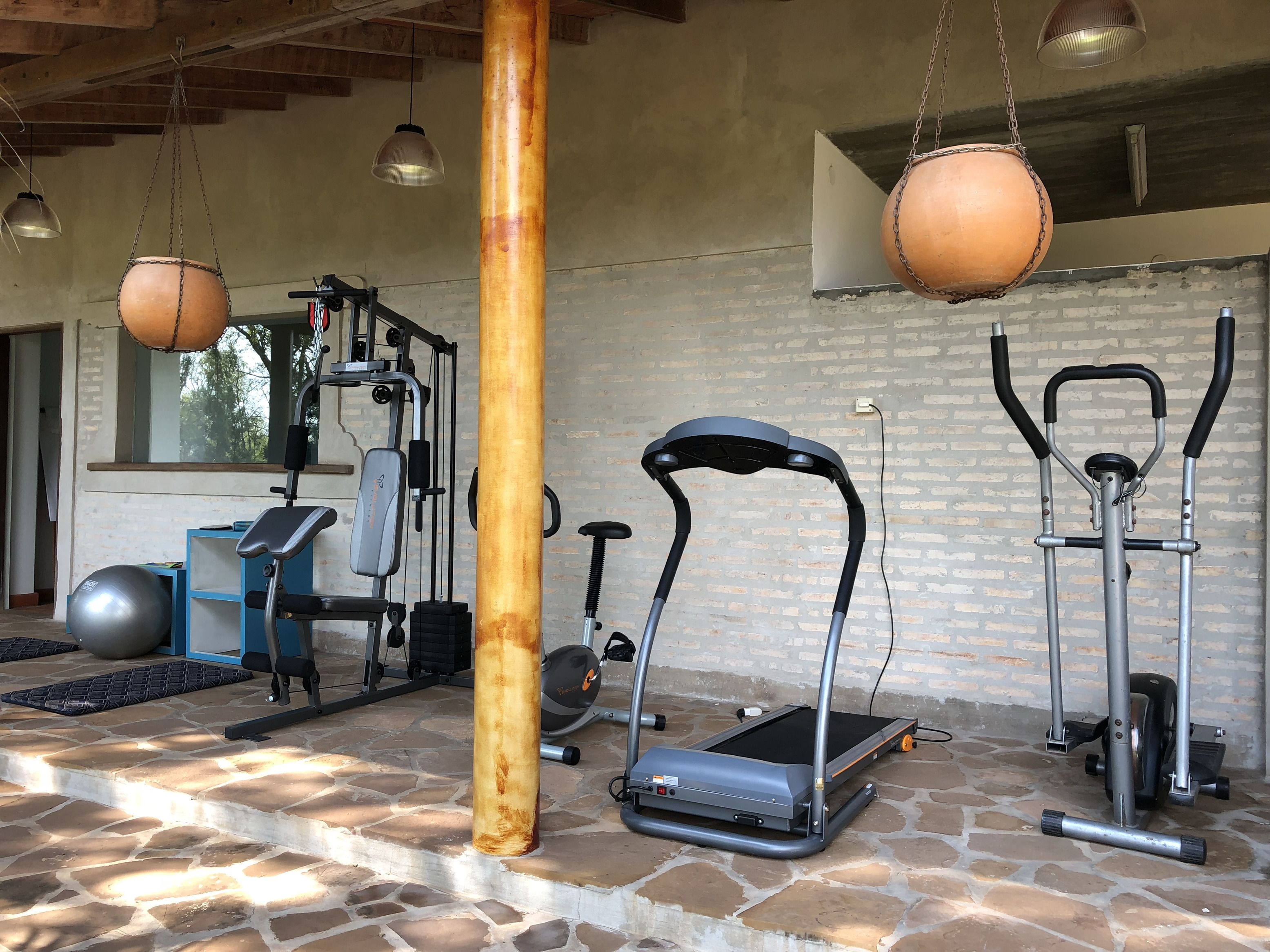 Un gimnasio con equipo de ejercicio, incluyendo una cinta de correr, elíptica y pesas.