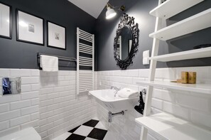 Een moderne badkamer met een wit wastafel, vloer in zwart-wit ruitpatroon en een grote spiegel met een sierlijk omlijsting.