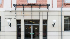A building entrance with a glass door, a sign reading "ul. TARTACZNA 2", and two wall-mounted light fixtures. - Happy Stay Old Town Tartaczna St. 27 A (Gdansk)
