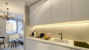 A modern kitchen with a white countertop, a sink, and a fruit bowl. There is a window with a view of buildings outside. - Happy Stay Old Town Tartaczna St. 27 A (Gdansk)