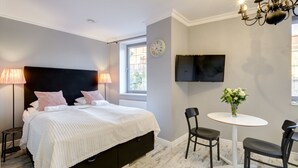 A bedroom with a bed, bedside lamps, a TV, a small table with chairs, and a window. - Happy Stay Old Town Tartaczna St. 27 A (Gdansk)