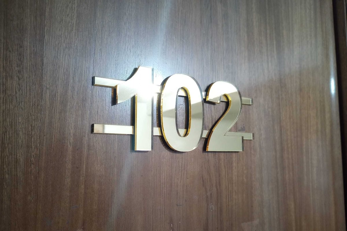 Un panneau métallique portant le chiffre « 102 », fixé sur une surface en bois.