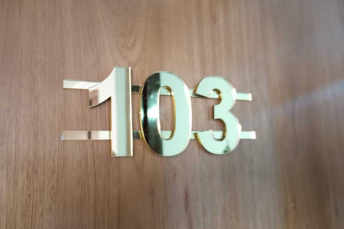 Une surface en bois portant un panneau métallique avec le numéro « 103 ».