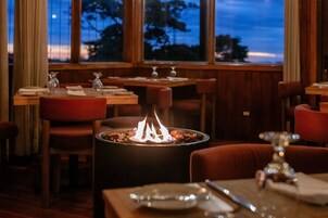 Un restaurante con una chimenea central, mesas y sillas de madera.