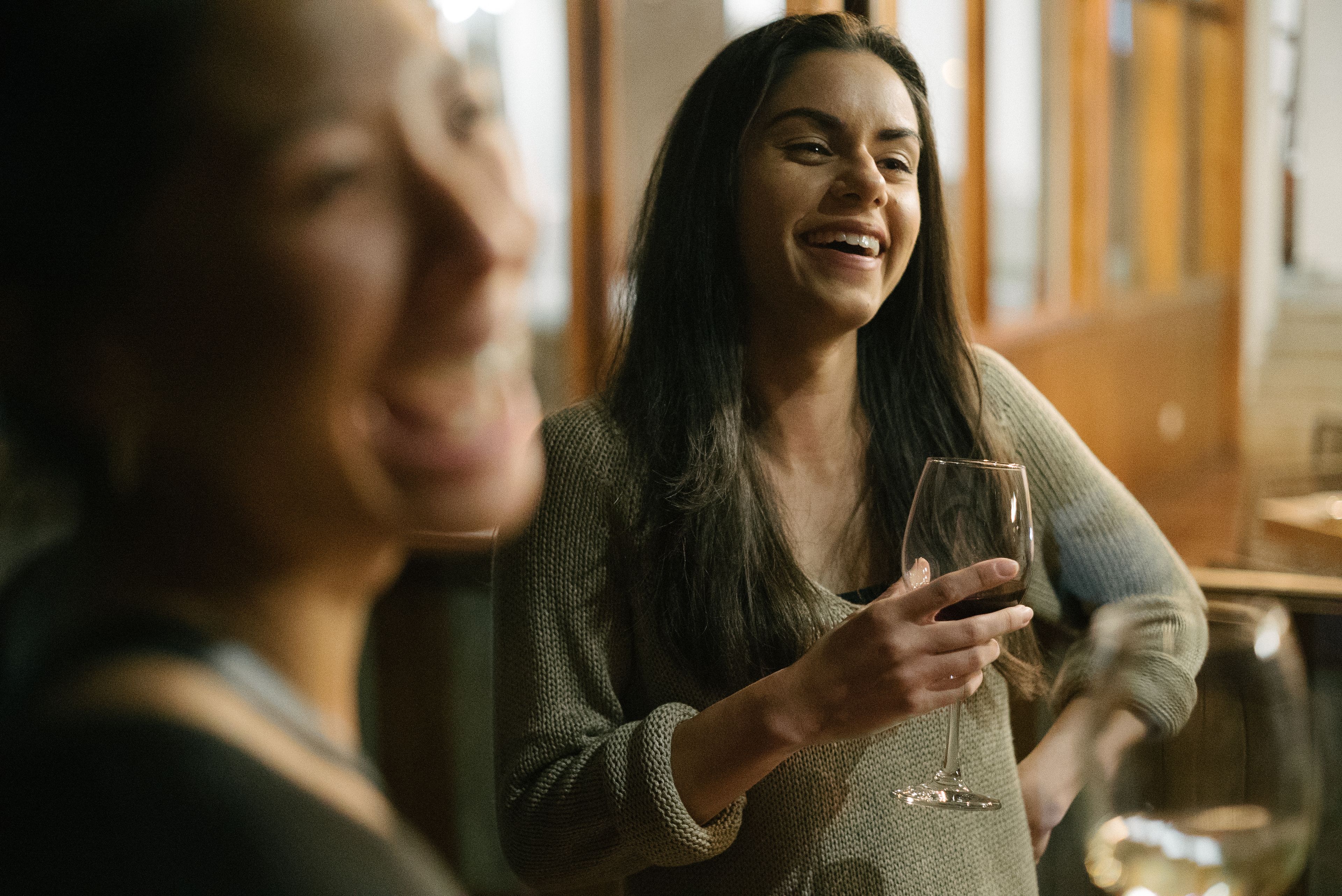 Una persona sosteniendo una copa de vino en una habitación con paneles de madera y una ventana.