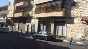 A multi-story building with a stone facade, balconies, and a parked car. - Hassan guest house (Nazareth)
