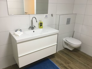 Une salle de bain avec un lavabo blanc, un miroir, des toilettes et un tapis bleu.