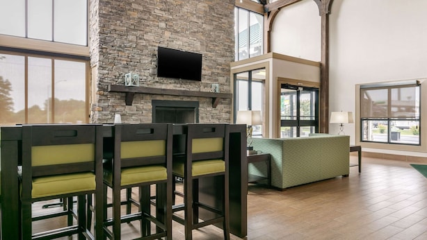 A spacious room with a stone fireplace, a flat-screen TV mounted above it, and a green upholstered sofa.