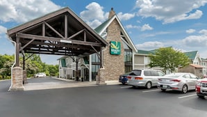 A Quality Inn with a covered entrance, stone pillars, and a clear sky.