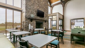 A restaurant with stone walls, a fireplace, and large windows offering a view of the outdoors.