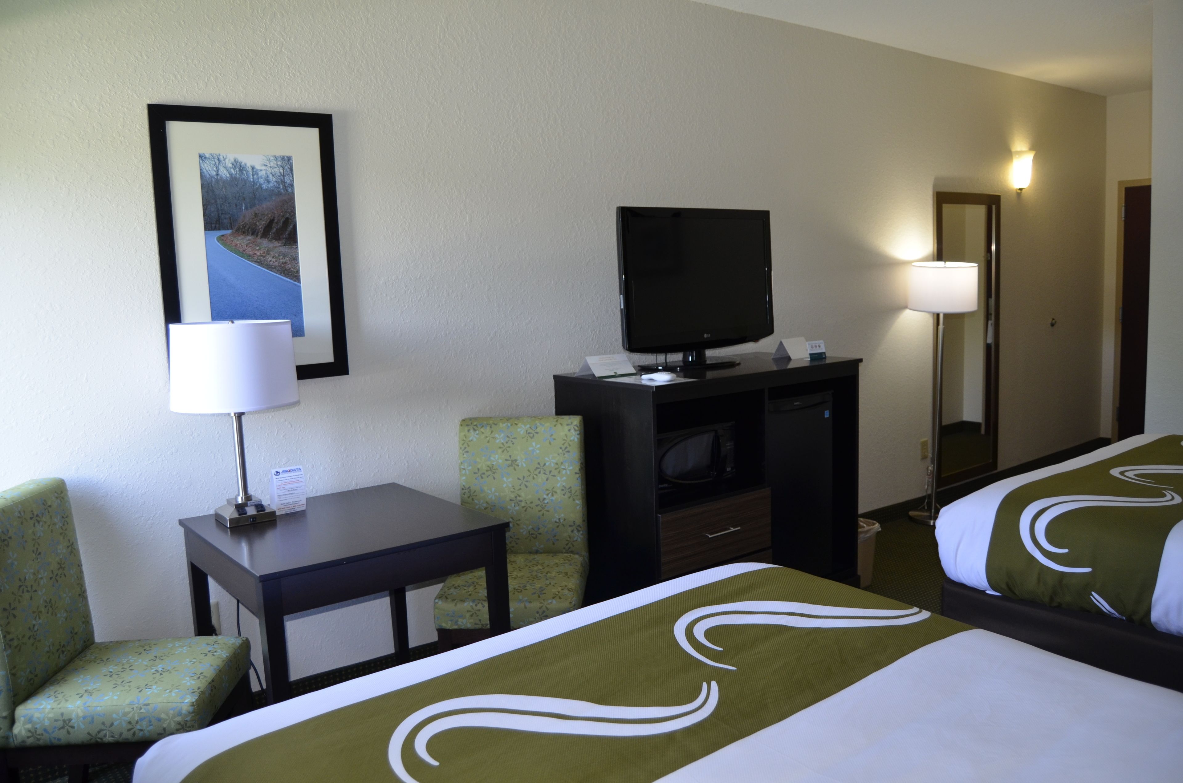 Ein Hotelzimmer mit Bett, Schreibtisch, Stuhl, Fernseher und Spiegel.