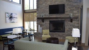 A lounge area with a stone fireplace, seating, and artwork.