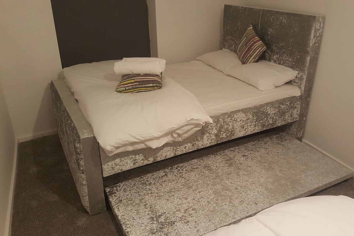 A single bed with a headboard, a pillow, and a folded blanket.