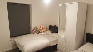 Ein Schlafzimmer mit Bett, Kleiderschrank und einem Fenster mit Jalousie.
