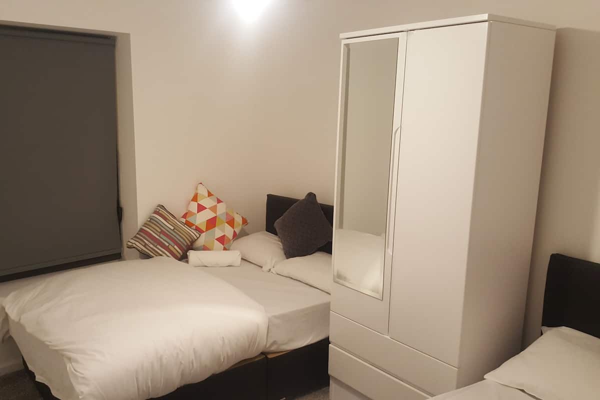 A bedroom with a bed, a wardrobe, and a window with a blind.