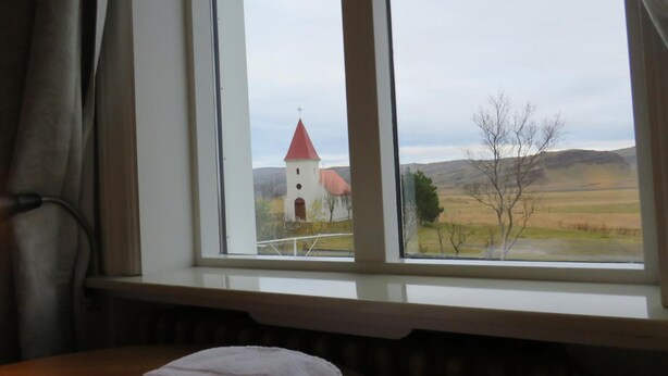 Ein Zimmer mit Blick auf eine Kirche und eine ländliche Gegend.