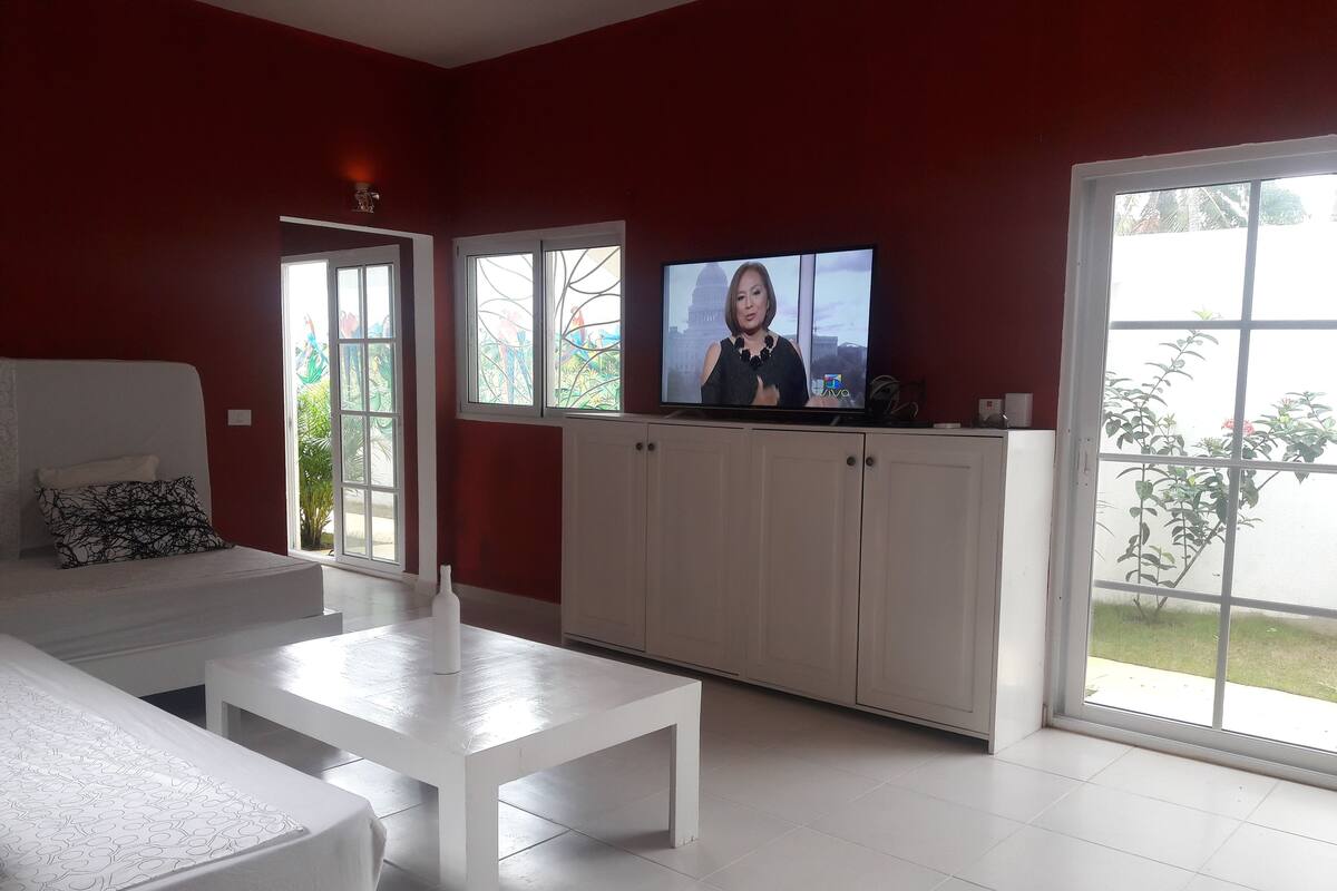 A modern living room with a white sofa, a white coffee table, and a television on a white cabinet.