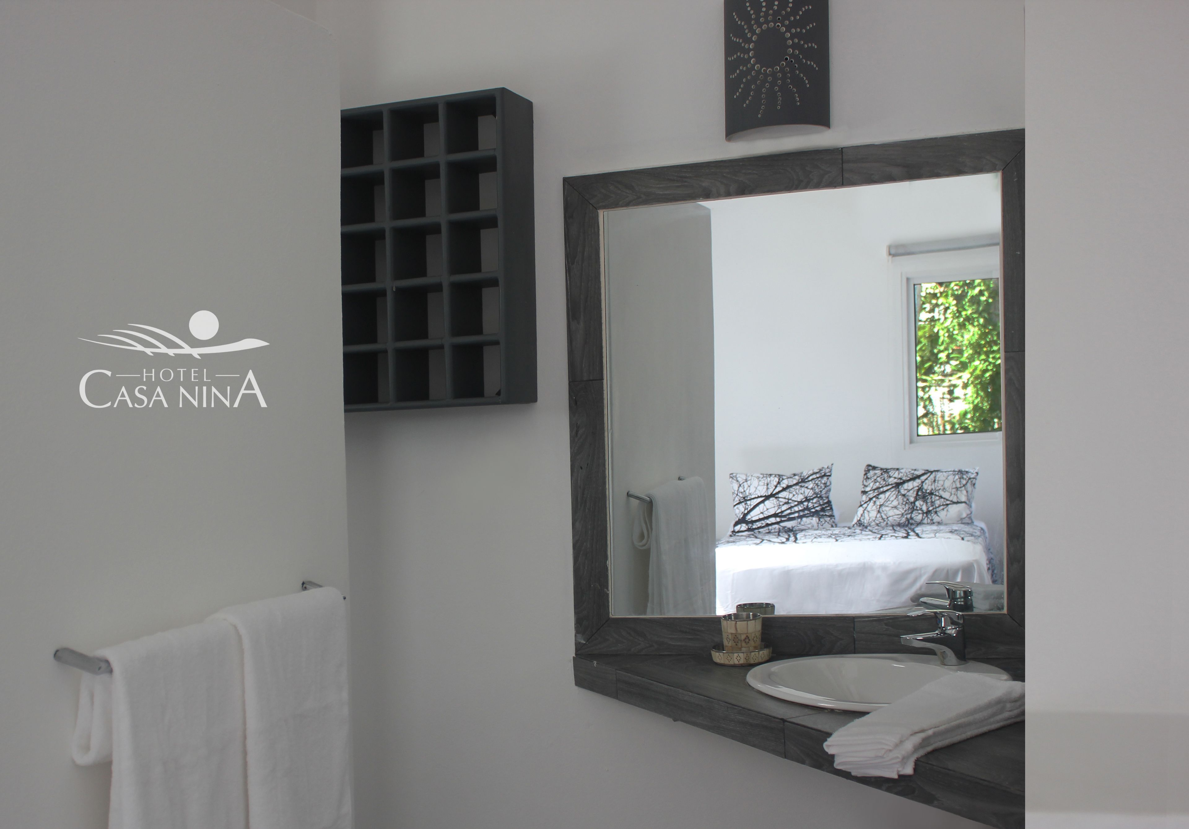 A modern bathroom with a large mirror, a white sink, and a towel rack.