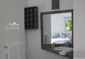 A modern bathroom with a large mirror, a white sink, and a towel rack. - Hotel Casa Nina (Las Terrenas)