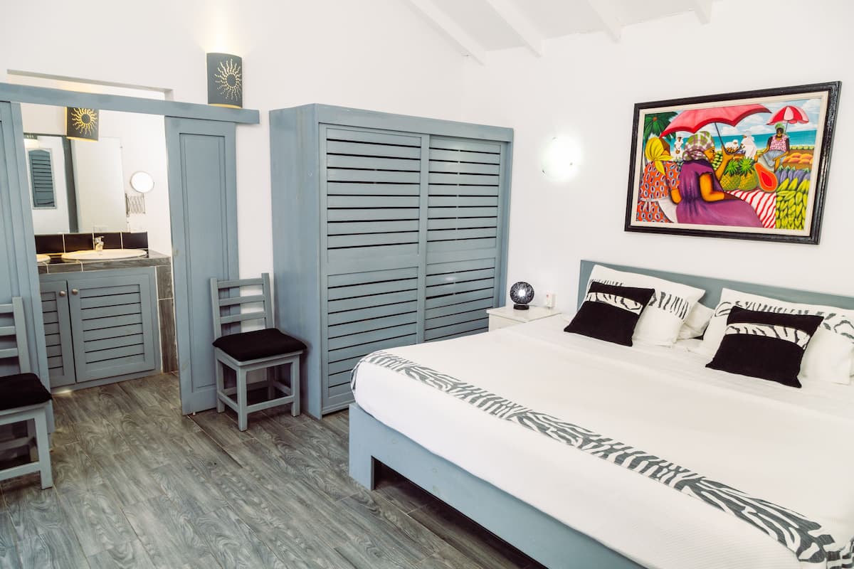 A bedroom with a bed, a nightstand, a chair, a wardrobe, and a painting on the wall.