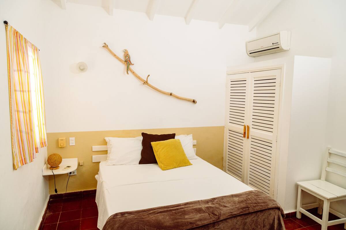 A neatly arranged bedroom with a bed, bedside table, and a chair.