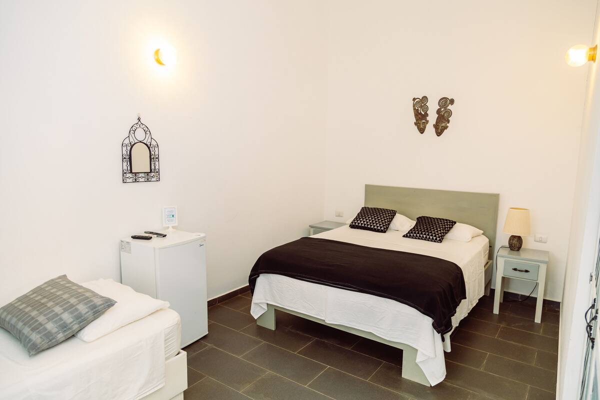 A neatly arranged bedroom with a bed, bedside tables, a small desk, and a chair.