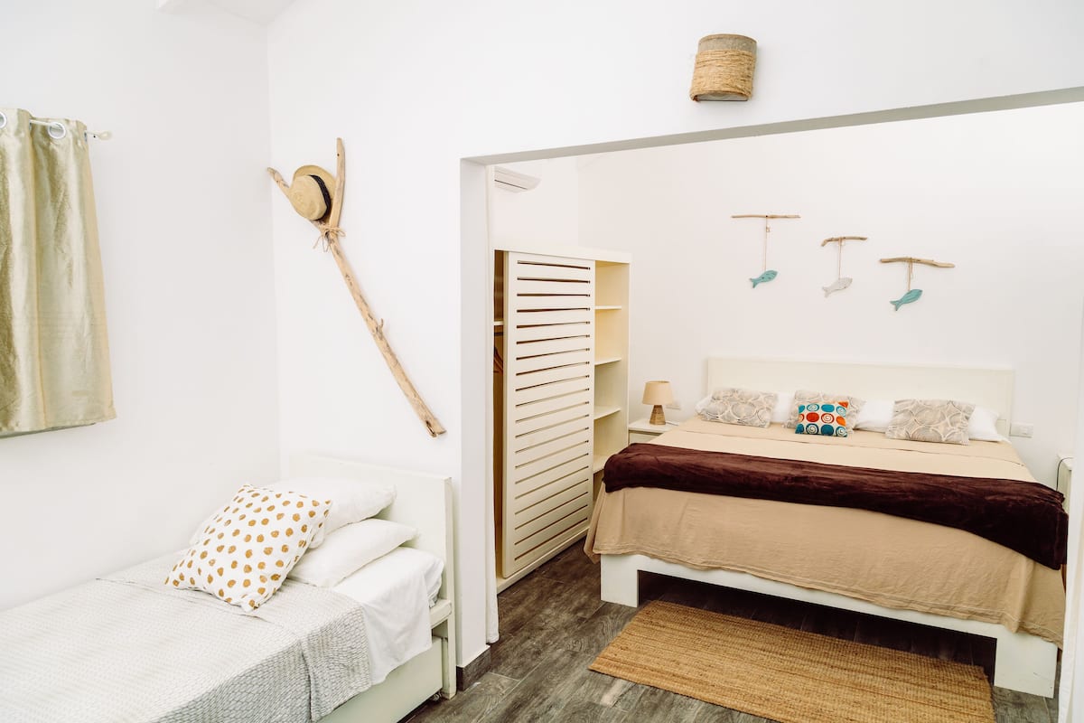 A bedroom with a bed, a small sofa, a wardrobe, and a hanging hat.