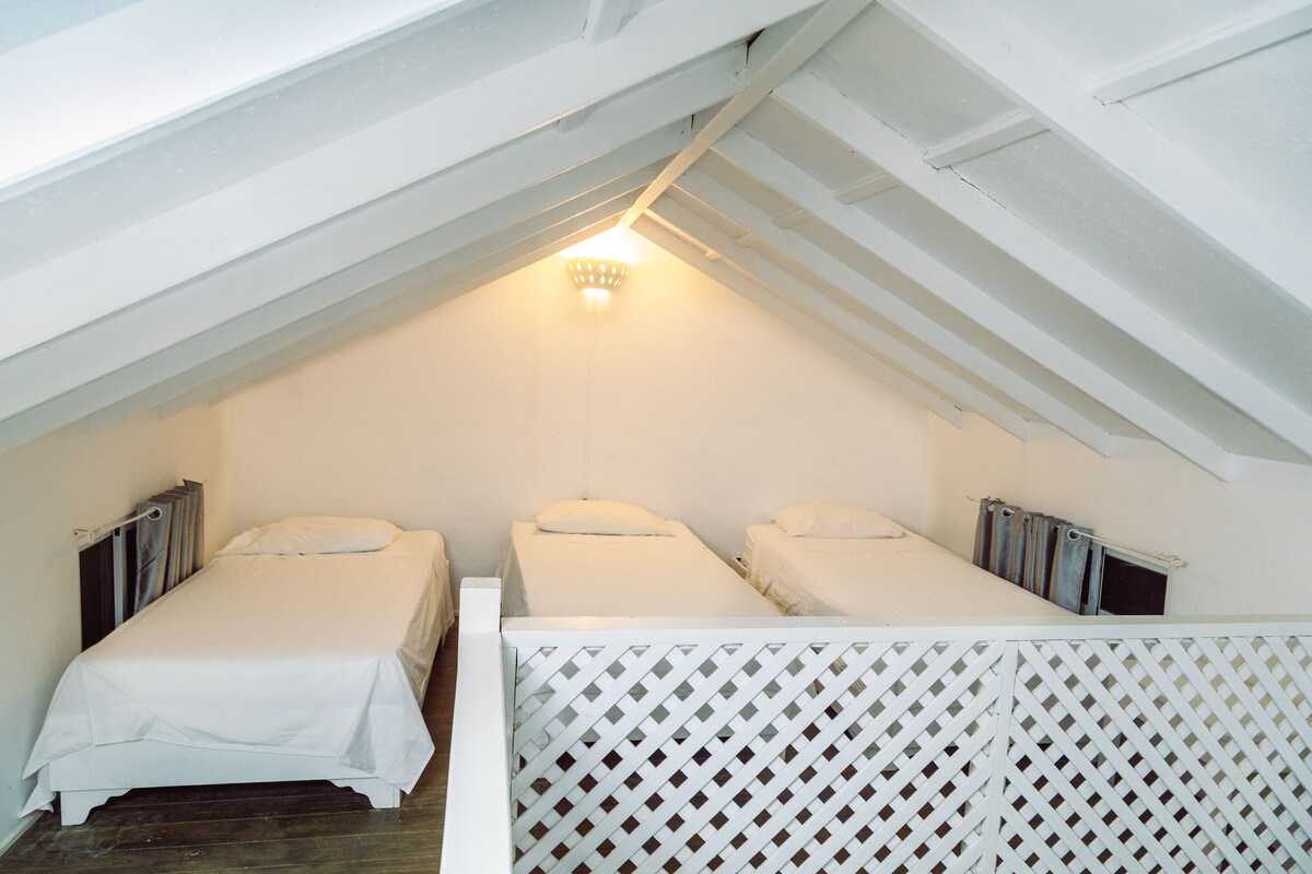 Ein kleines Zimmer im Dachgeschoss mit zwei Einzelbetten, einer weißen Decke und einer geneigten Decke.