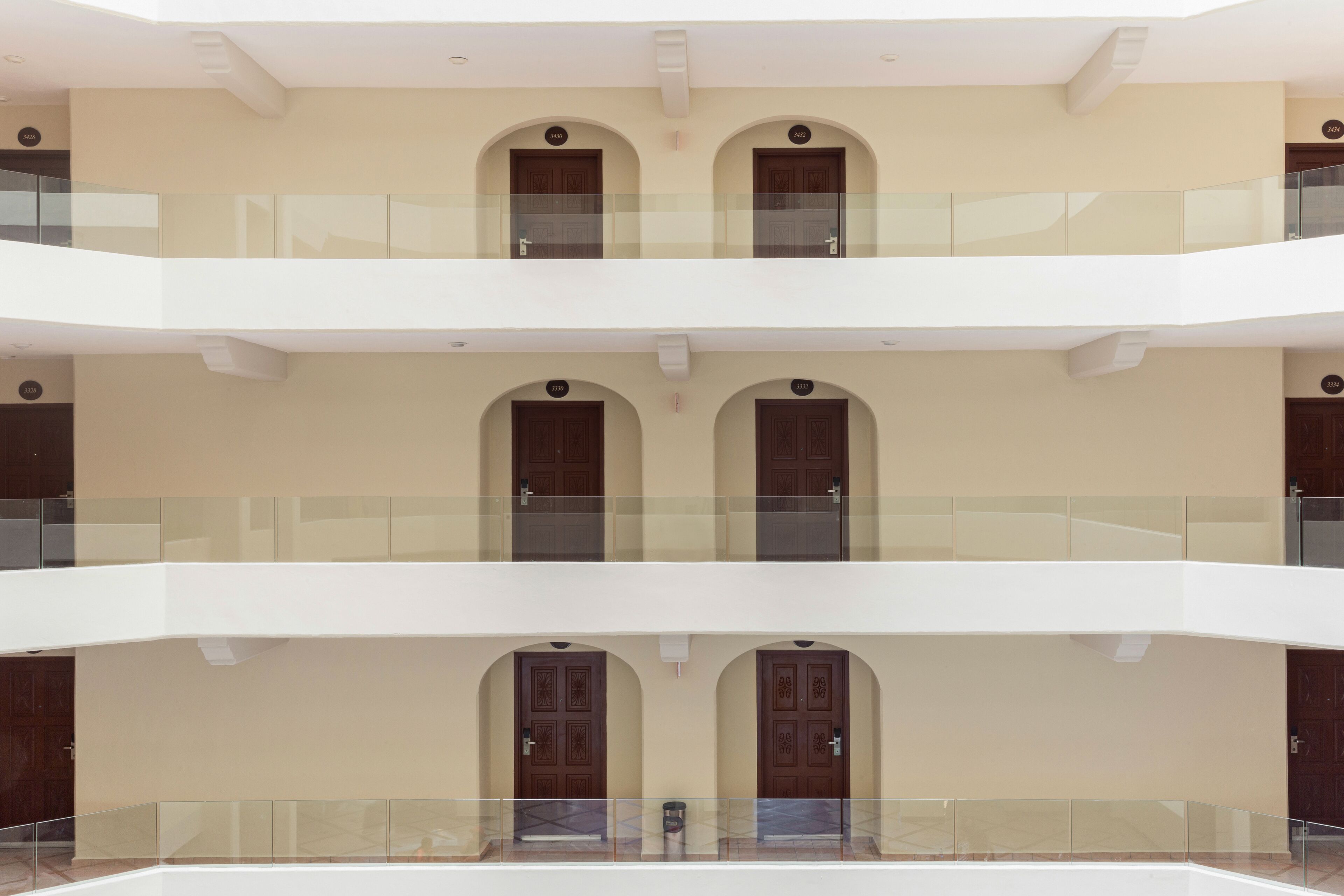 Un intérieur à plusieurs niveaux, avec des portes en arc de cercle et une rambarde en verre au niveau supérieur.