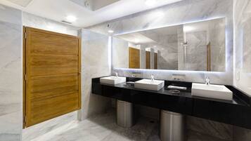 Une salle de bain moderne avec deux lavabos, un grand miroir et une porte en bois.