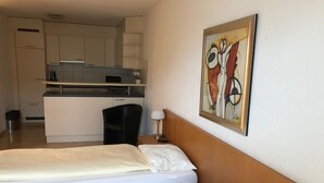 Habitació d'hotel amb dos llits, una cuineta i un quadre a la paret.