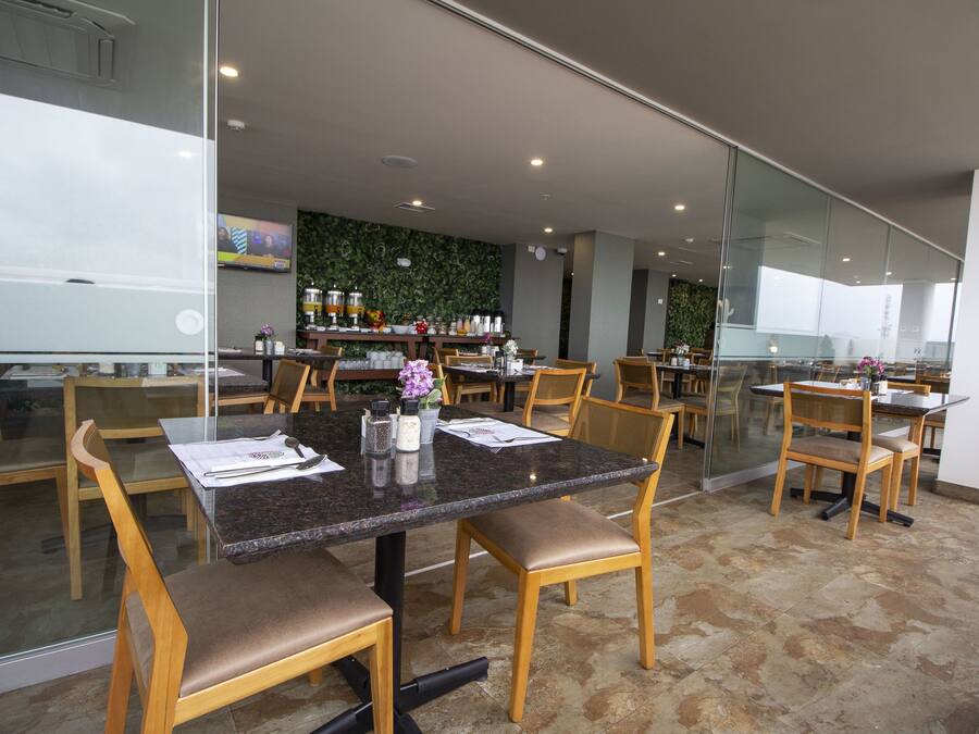 A modern dining area with glass partitions, wooden chairs, and a central table with a menu.