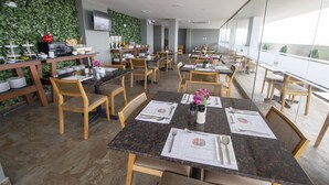 A restaurant with multiple tables and chairs, a green wall, and a TV mounted on the wall. - Tierra Viva Trujillo (Trujillo)