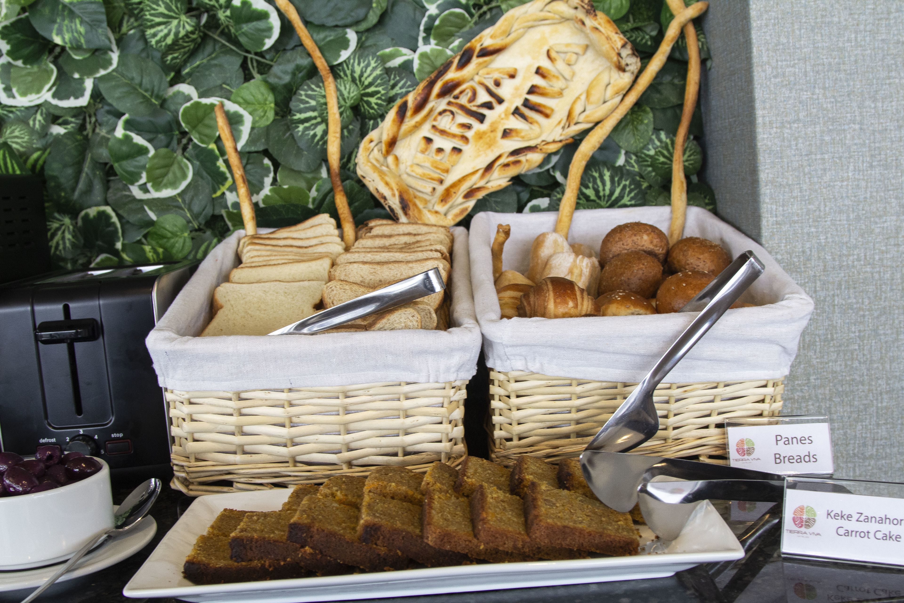 A buffet with baskets of bread, rolls, and a plate of carrot cake.