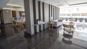 A modern lobby with a bar area, seating, and a large window offering a view of the building's exterior. - Tierra Viva Trujillo (Trujillo)