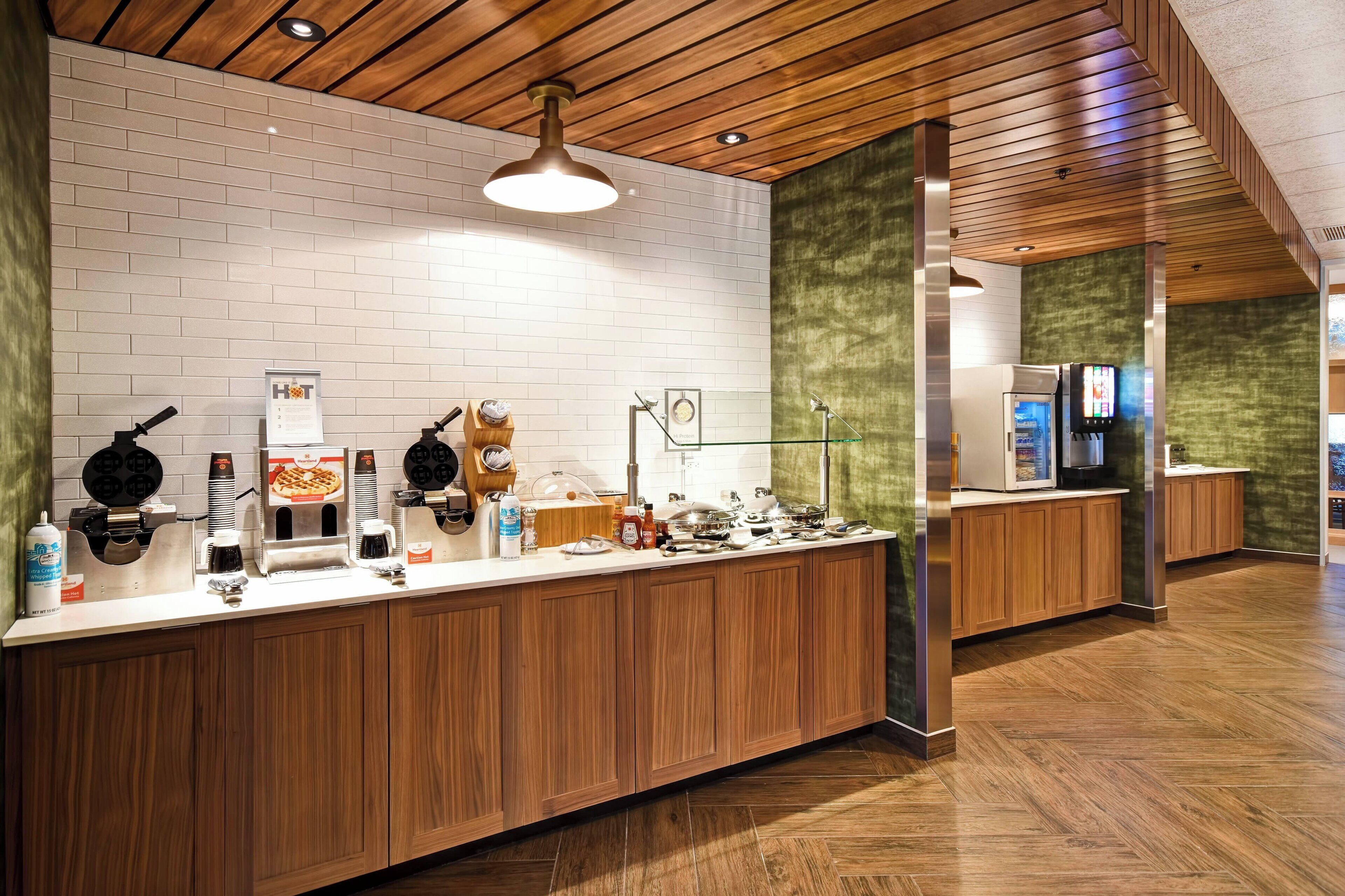 Una cocina moderna con encimera de madera, varios electrodomésticos y pared de ladrillo.