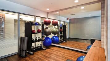 A gym with exercise equipment, including kettlebells, medicine balls, and a weight rack.