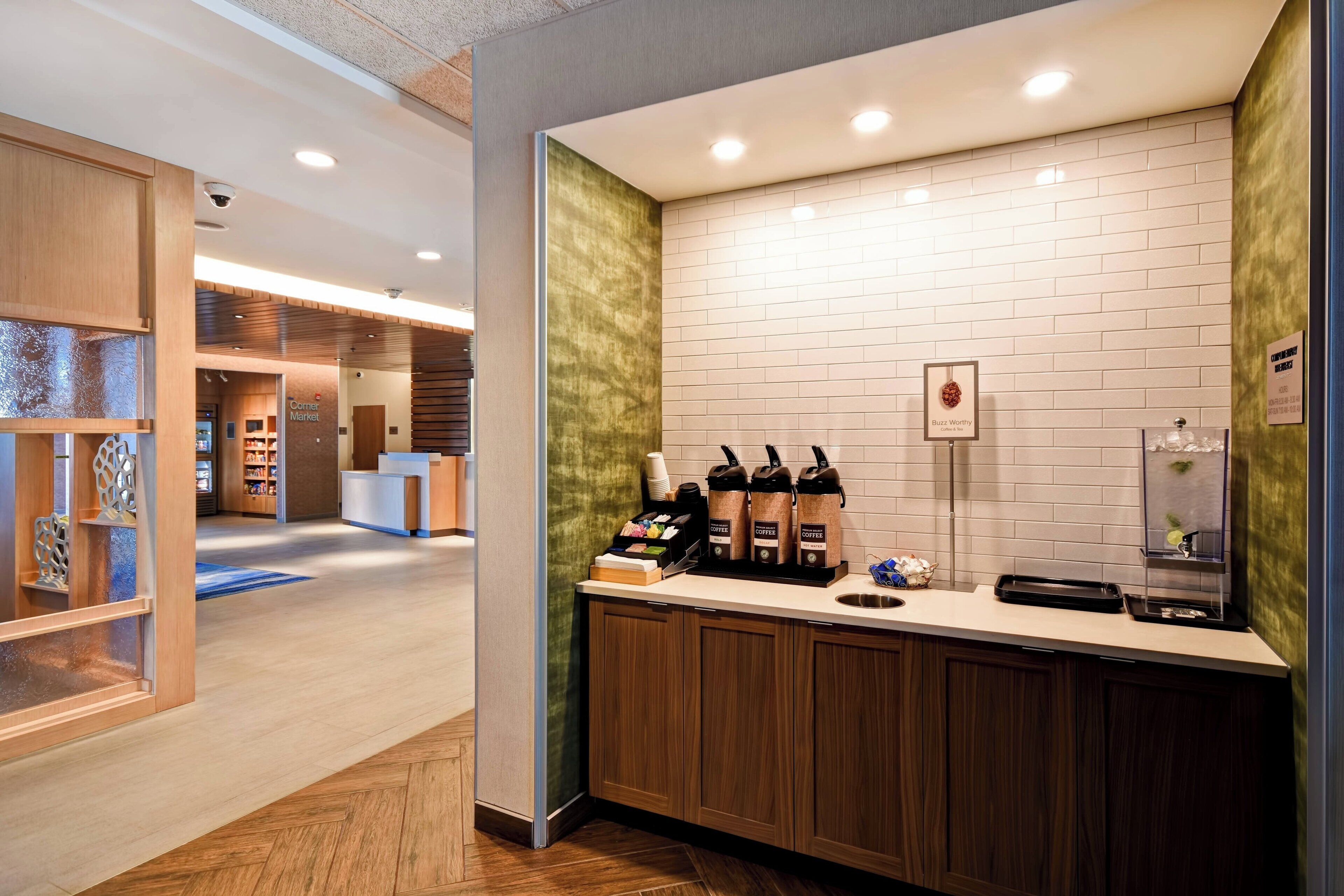Una estación de café moderna con pared de ladrillo blanco, armarios de madera y una máquina de café.